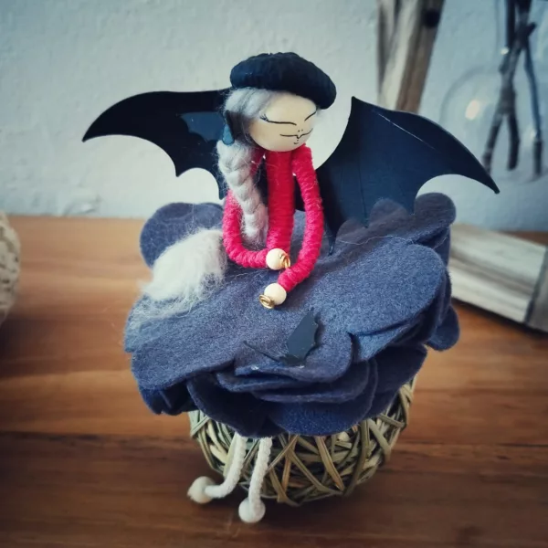 fée avec jupe en feutrine, aile de chauve-souris en papier et chapeau de gland noir sur la tête