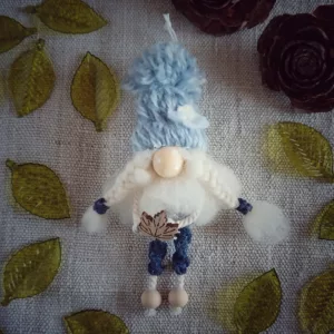 magnet avec bonnet en laine bleu, barbe en laine cardée, nez en perle de bois, pantalon bleu en macramé