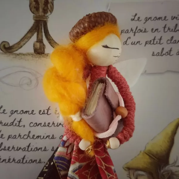 fée réalisée à la main, tient un livre dans ses mains, jupe en chute de tissu et béret en cupule